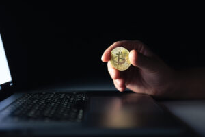 bitcoin-coin-near-laptop-black-background-finance-crypto-money-concept-scaled