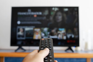 hand-holding-remote-control-while-looking-new-movie-scaled